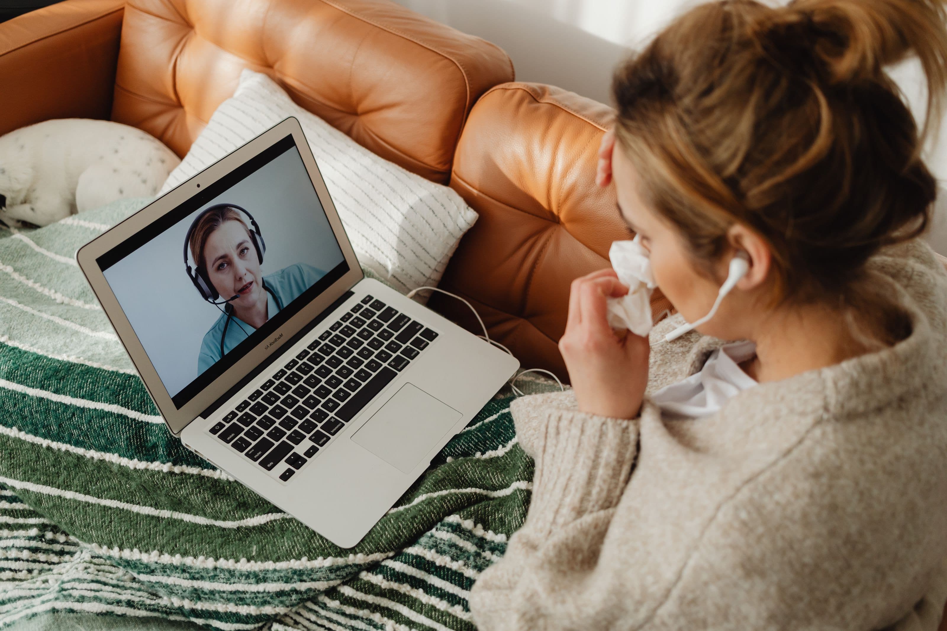 A patient on her sofa on a video visit with her physician